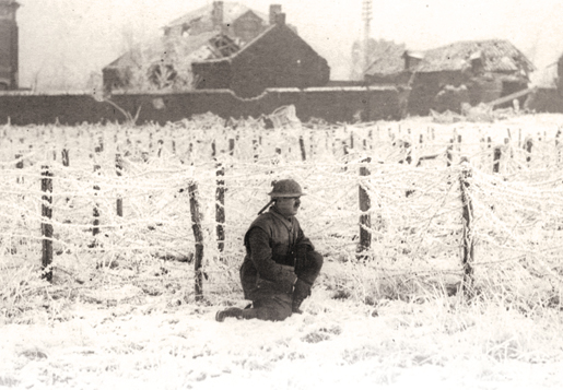 A soldier sits among a field of frost-covered barbed wire. [PHOTO: ARCHIVES OF ONTARIO—C224-0-0-10-25]